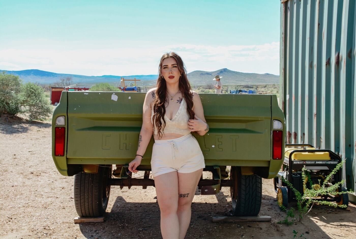 A woman leaning against a pickup truck bed in a desert landscape, representing a safe, planned meetup between matches