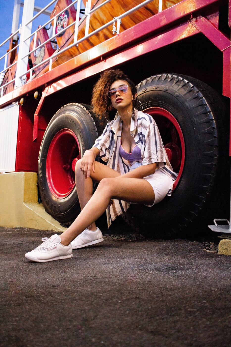 A woman sitting beside a large truck wheel, representing the reality of building a relationship around a driving schedule